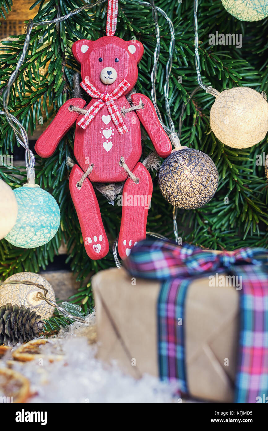 Rosso orso di legno appeso nel ramo di Natale decorato con illuminato palle di Natale Foto Stock