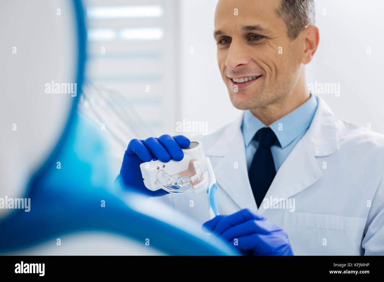 Gioioso dentista maschio tenendo un modello di bocca Foto Stock