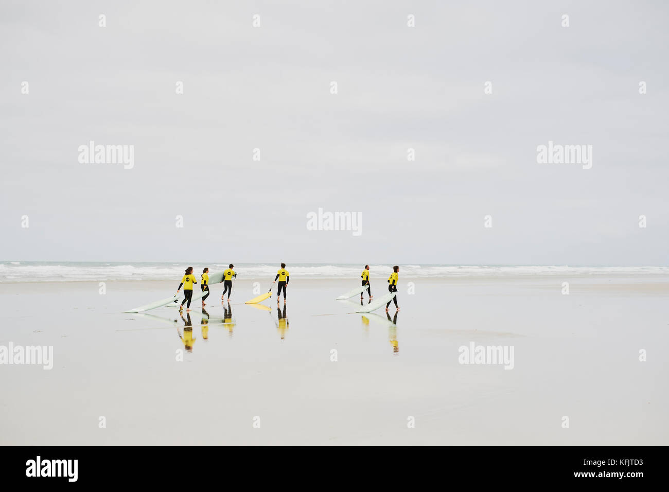 Scuola di surf gli studenti in giallo pettorine con le loro tavole da surf alla Plage de la Torche Plomeur Finistere Bretagna Francia Foto Stock