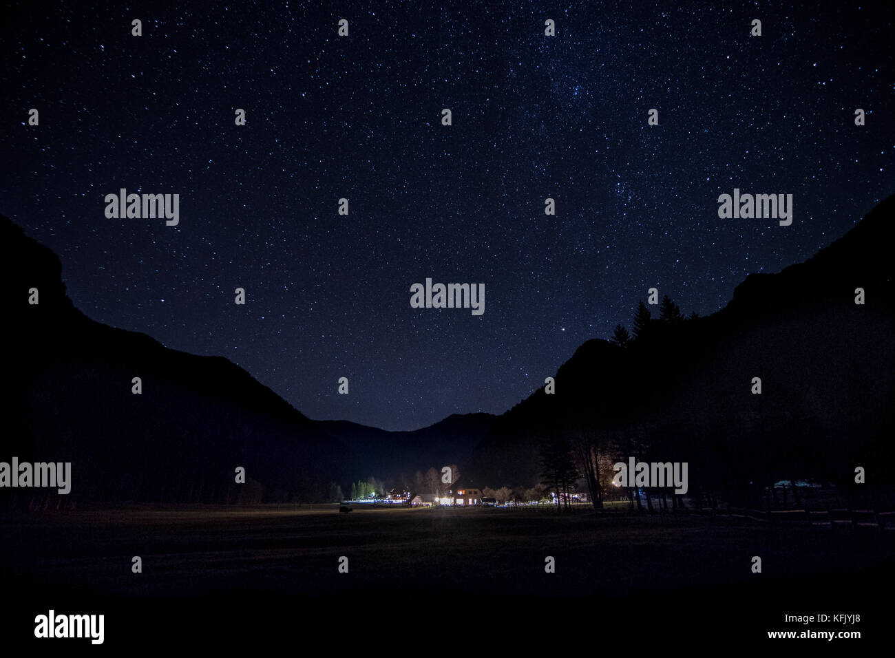 Paesaggio notturno, illuminato Alpine lodge, silhouette di montagna e cielo stellato Foto Stock