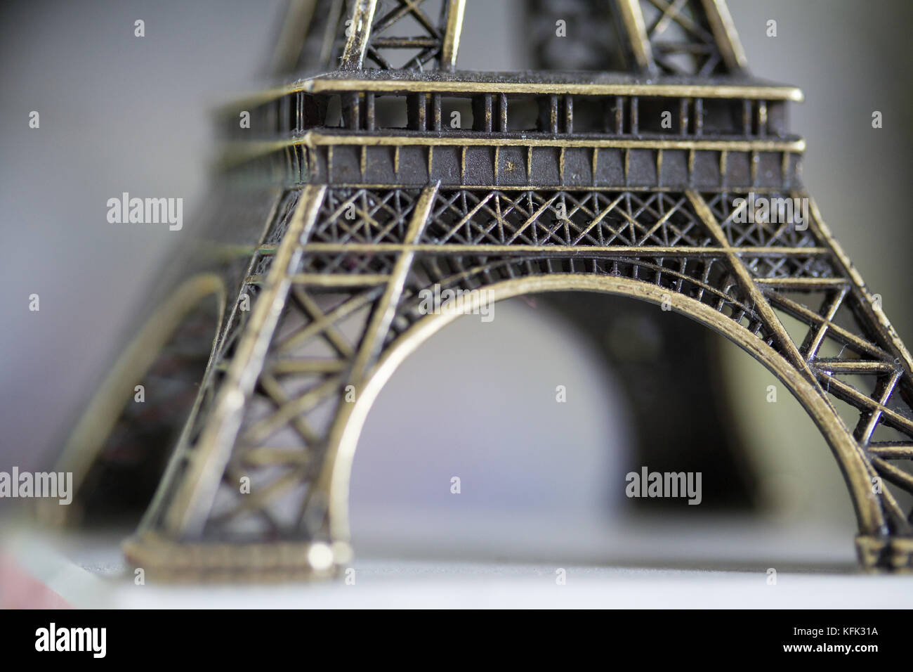 Una piccola figurina fotografata in un modo che isola la base della Torre Eiffel, Parigi, Francia Foto Stock