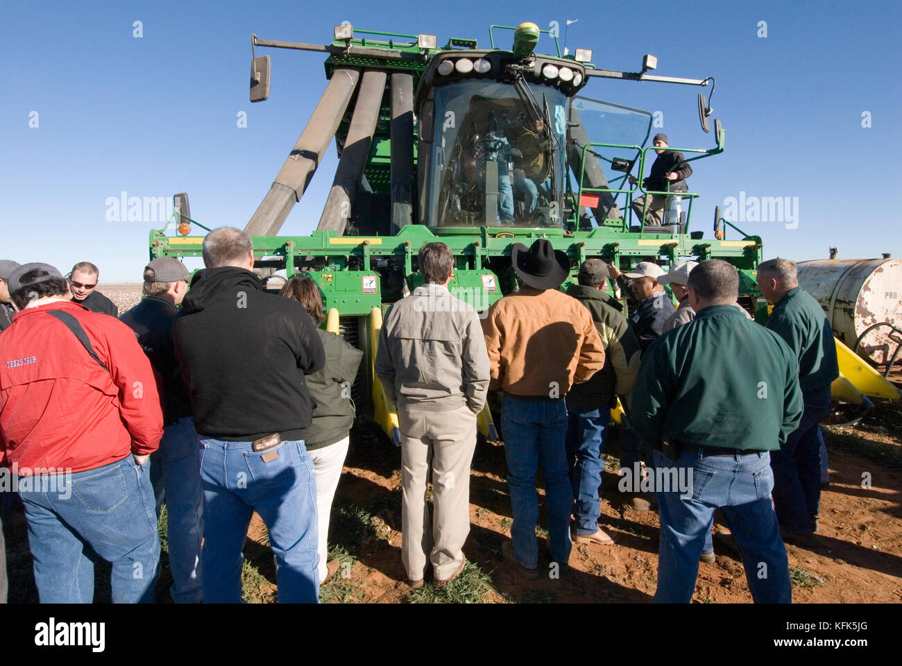 Nuovo trattore John Deere 6 fila raccoglitrice di cotone che rende i moduli rotondo nel campo mentre sotto lo sviluppo di essere visto e studiato dal concessionario John Deere dipendenti Foto Stock