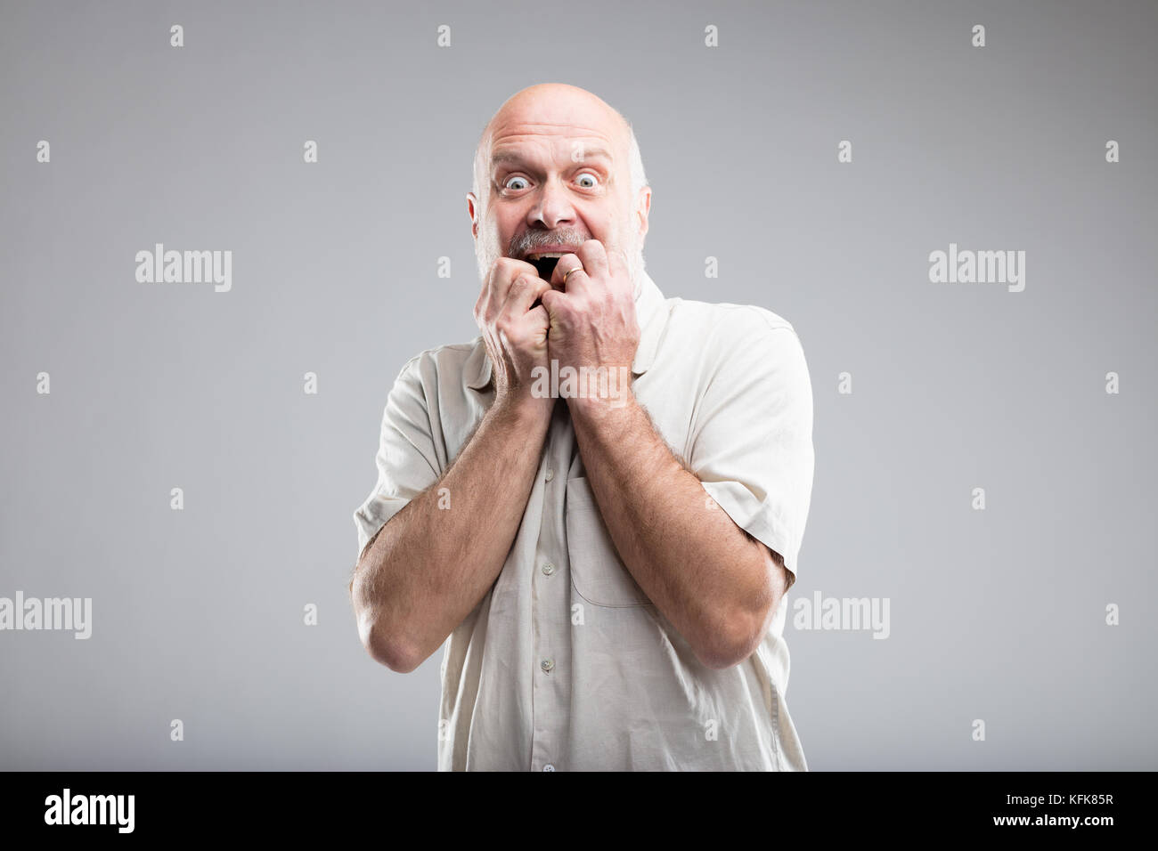 Frightened vecchio in un esagerato expressino della paura - studio ritratto su sfondo neutro Foto Stock