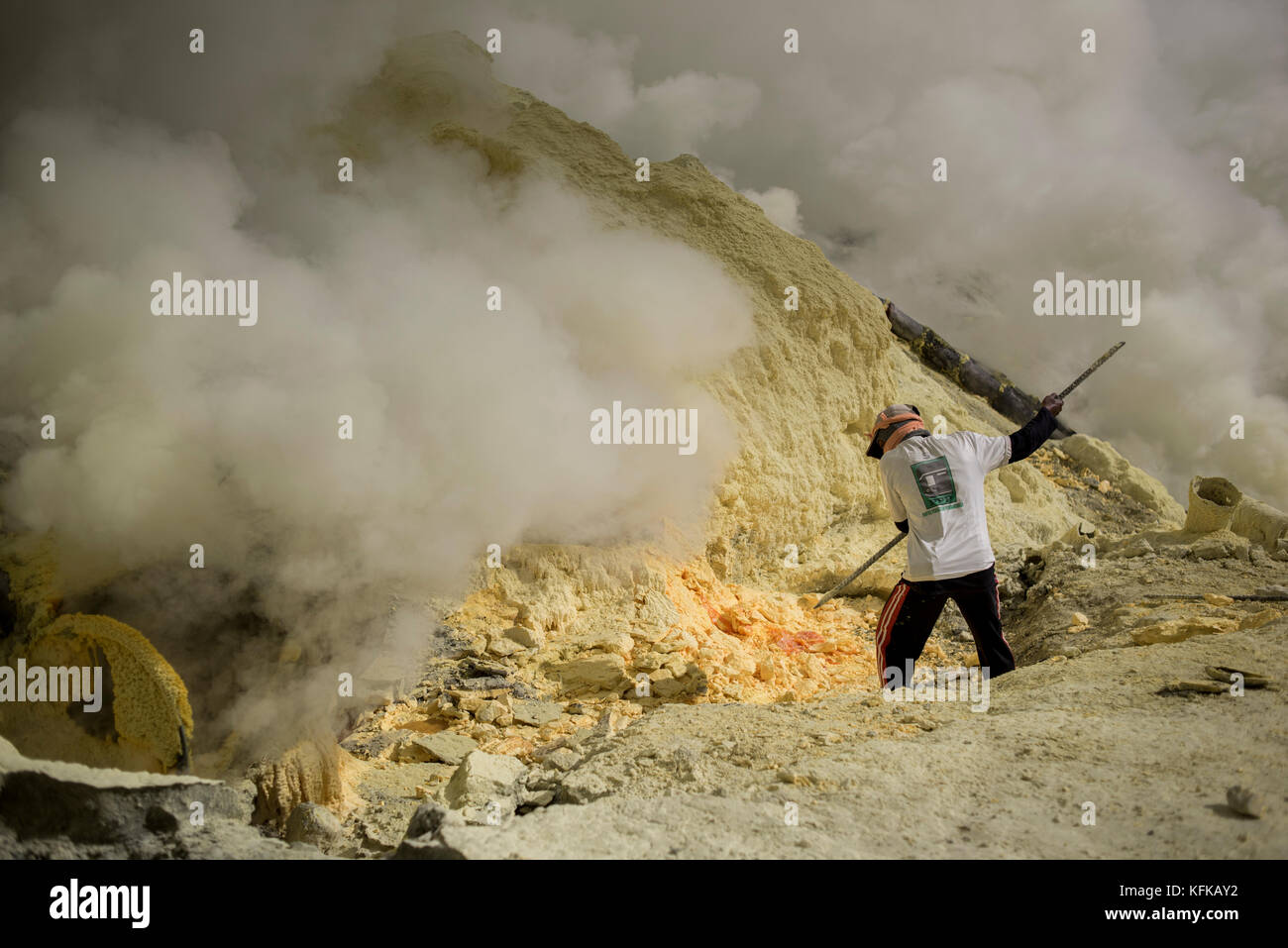 Un minatore estrae zolfo rocce dal kawah ijen vulcano, Java Orientale, Indonesia. Foto Stock