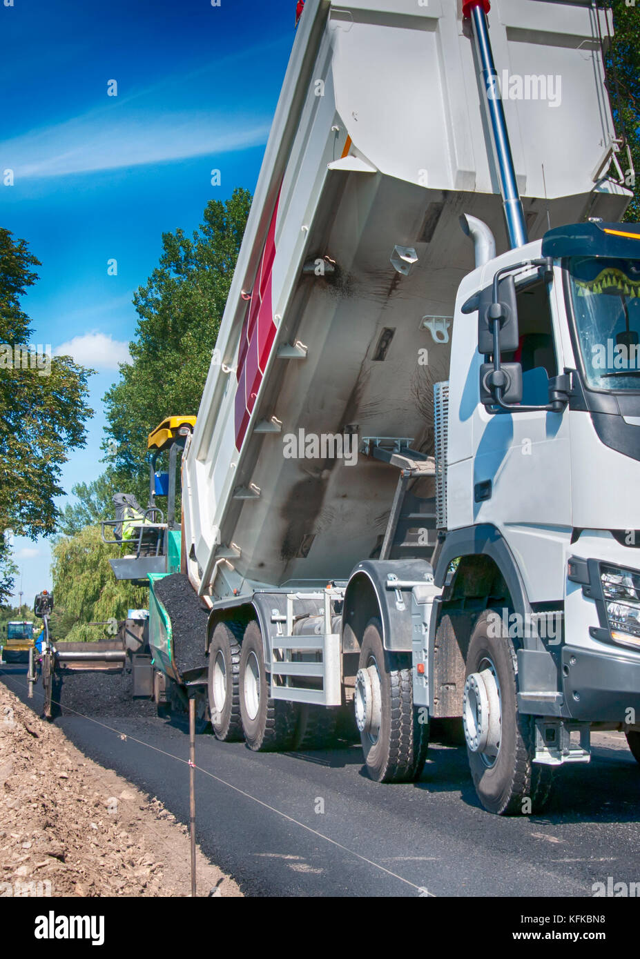 Asfalto lastricatore macchina durante la costruzione di strade, la costruzione di strade equipaggio applicare il primo strato di asfalto Foto Stock