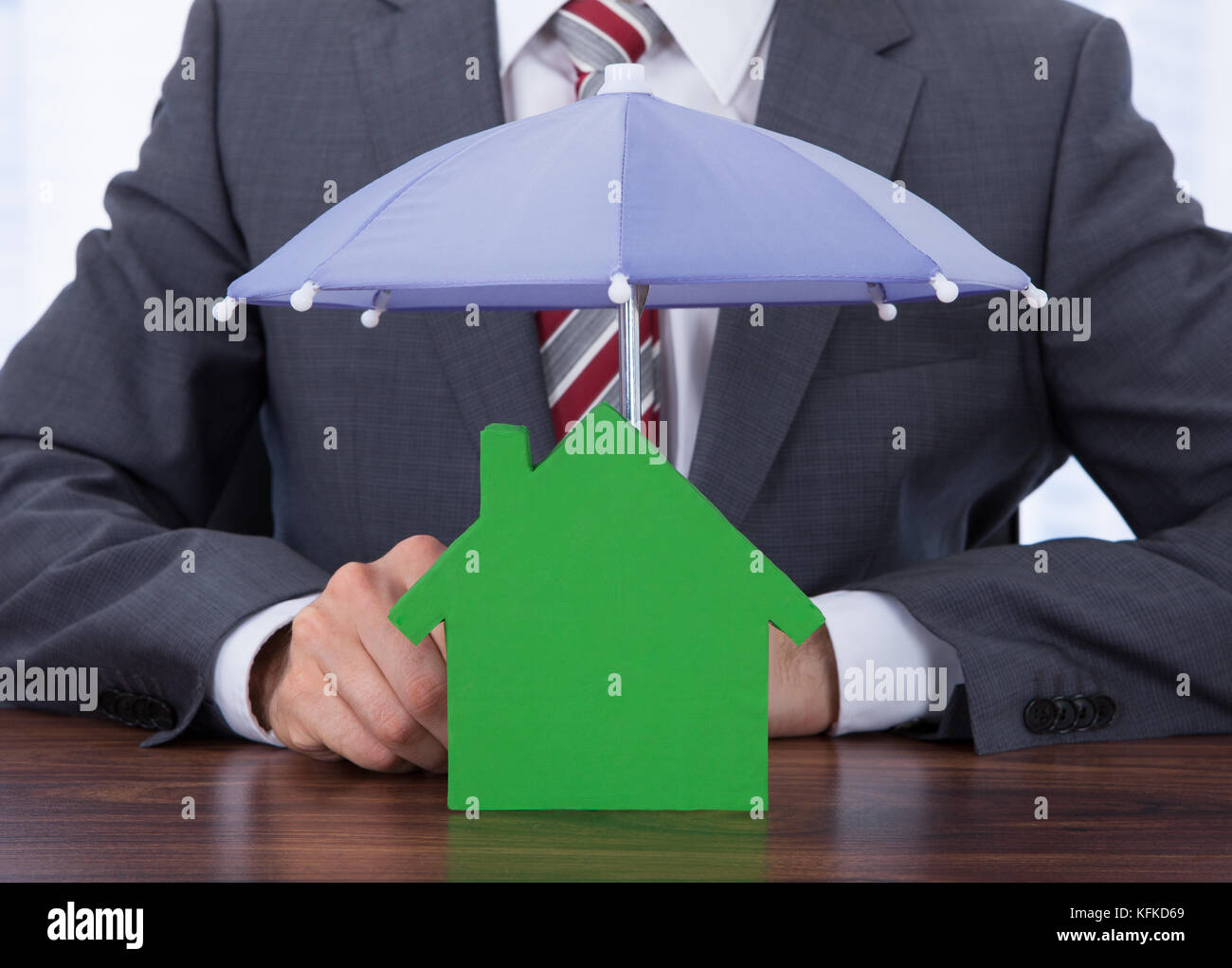 Sezione mediana di imprenditore il ricovero di casa con ombrellone al desk Foto Stock