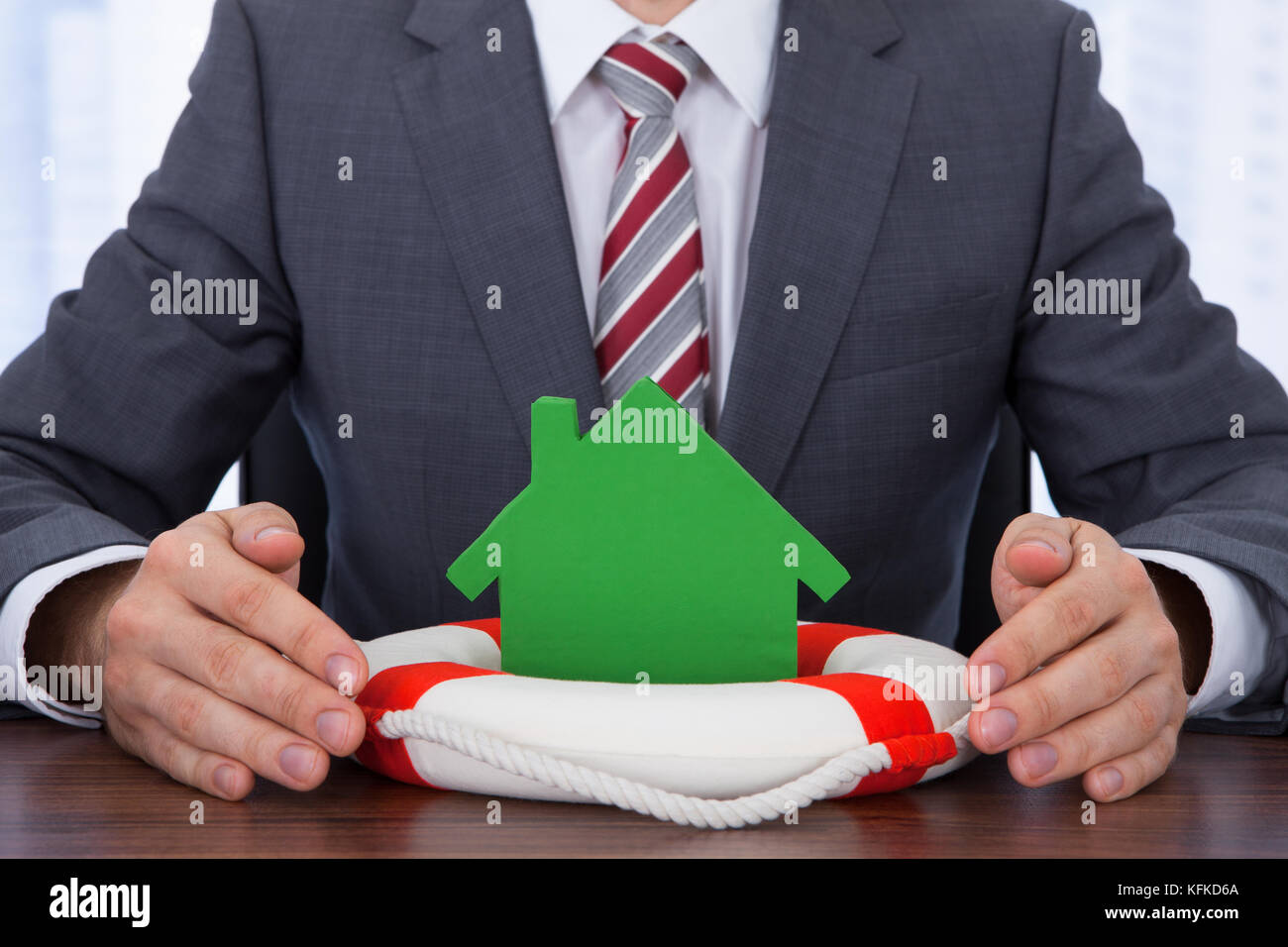 Sezione mediana di imprenditore il ricovero di casa con salvagente a scrivania Foto Stock