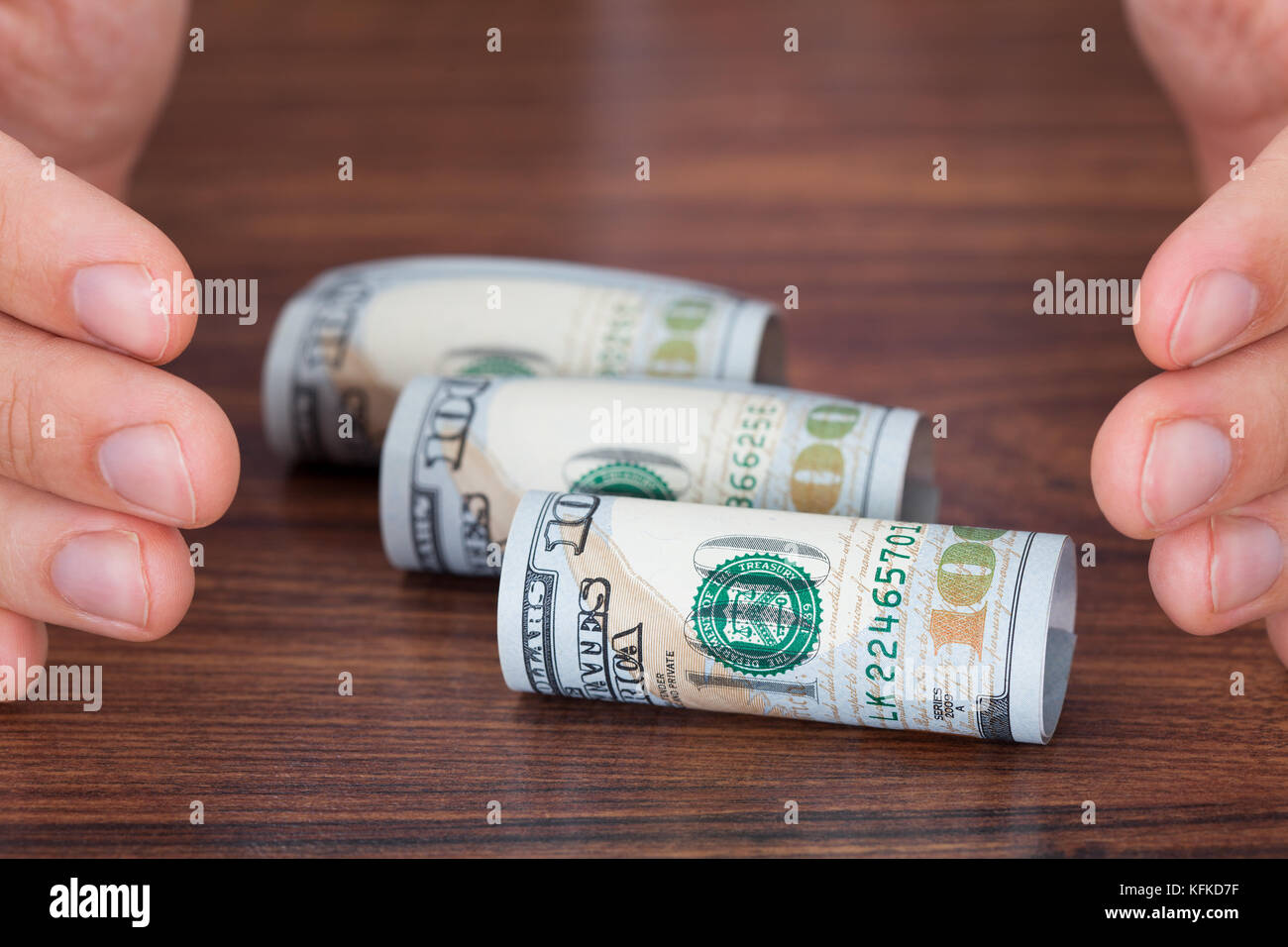 Immagine ritagliata delle mani la protezione di laminati di banconote sul tavolo Foto Stock