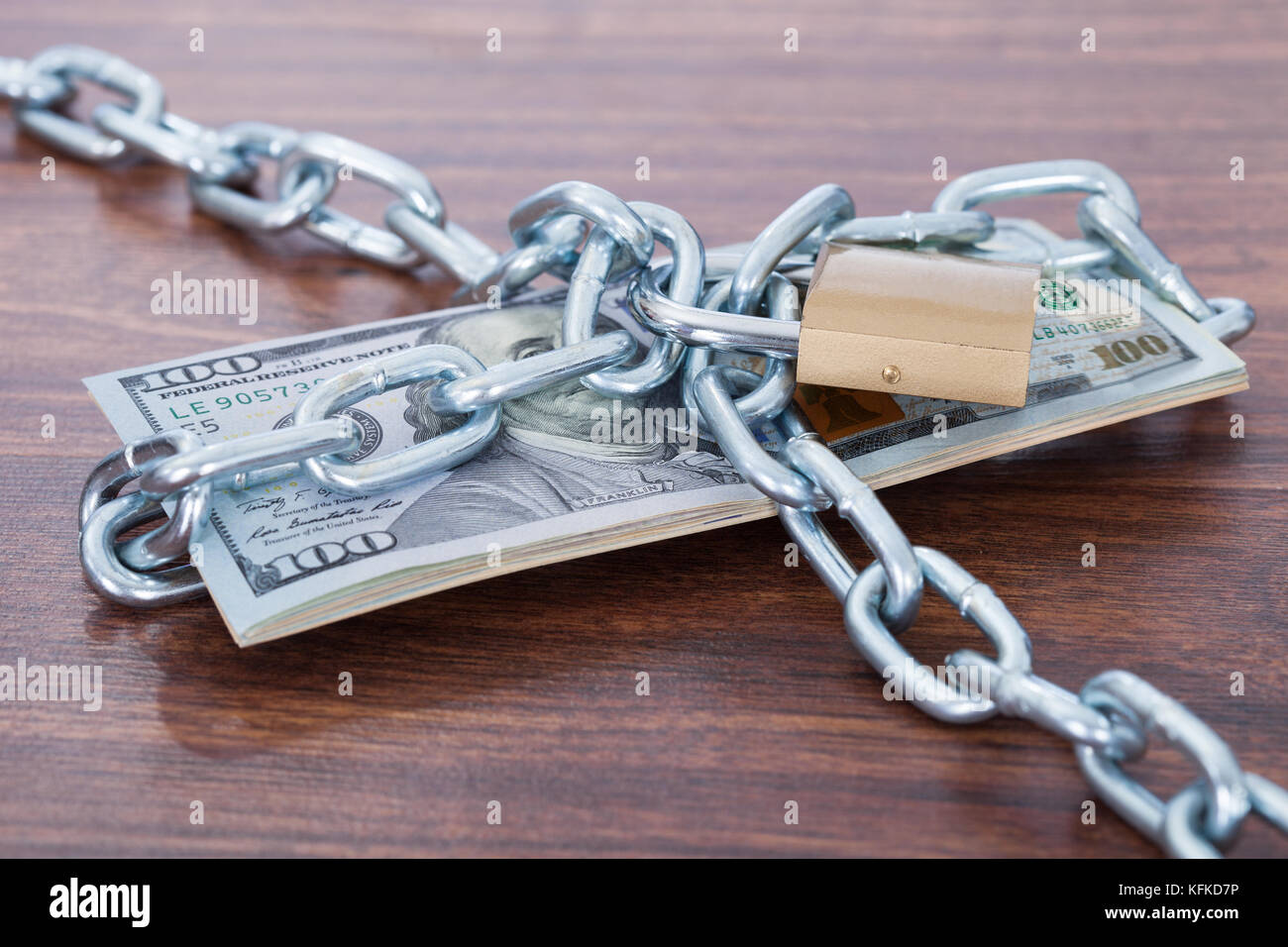 Centinaia di dollari di banconote con catena e un lucchetto sul tavolo Foto Stock