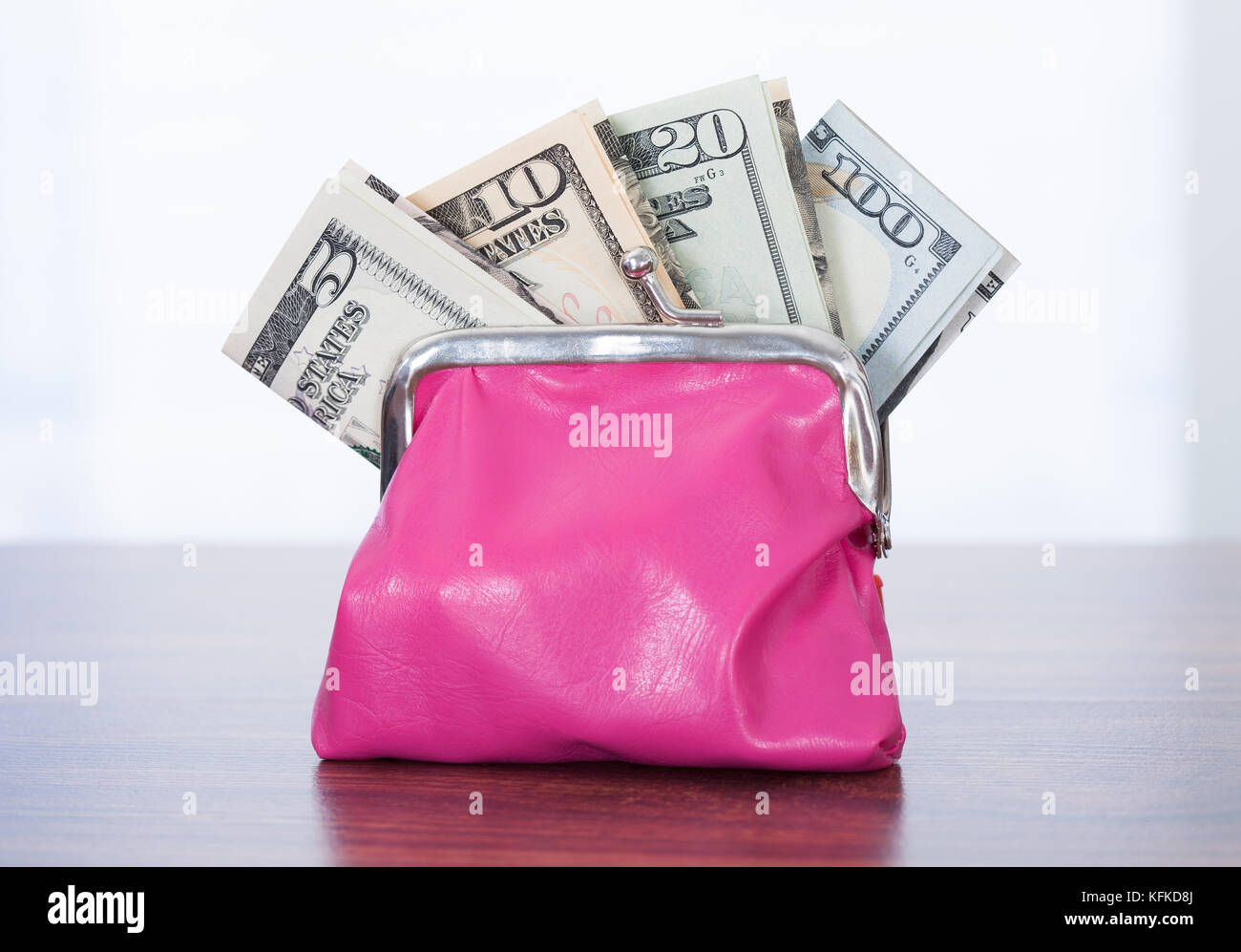 Varietà di fatture del dollaro nella borsa rosa sul tavolo Foto Stock