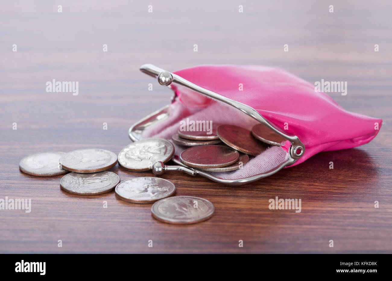 Primo piano di monete spillato dal portamonete rosa sul tavolo Foto Stock