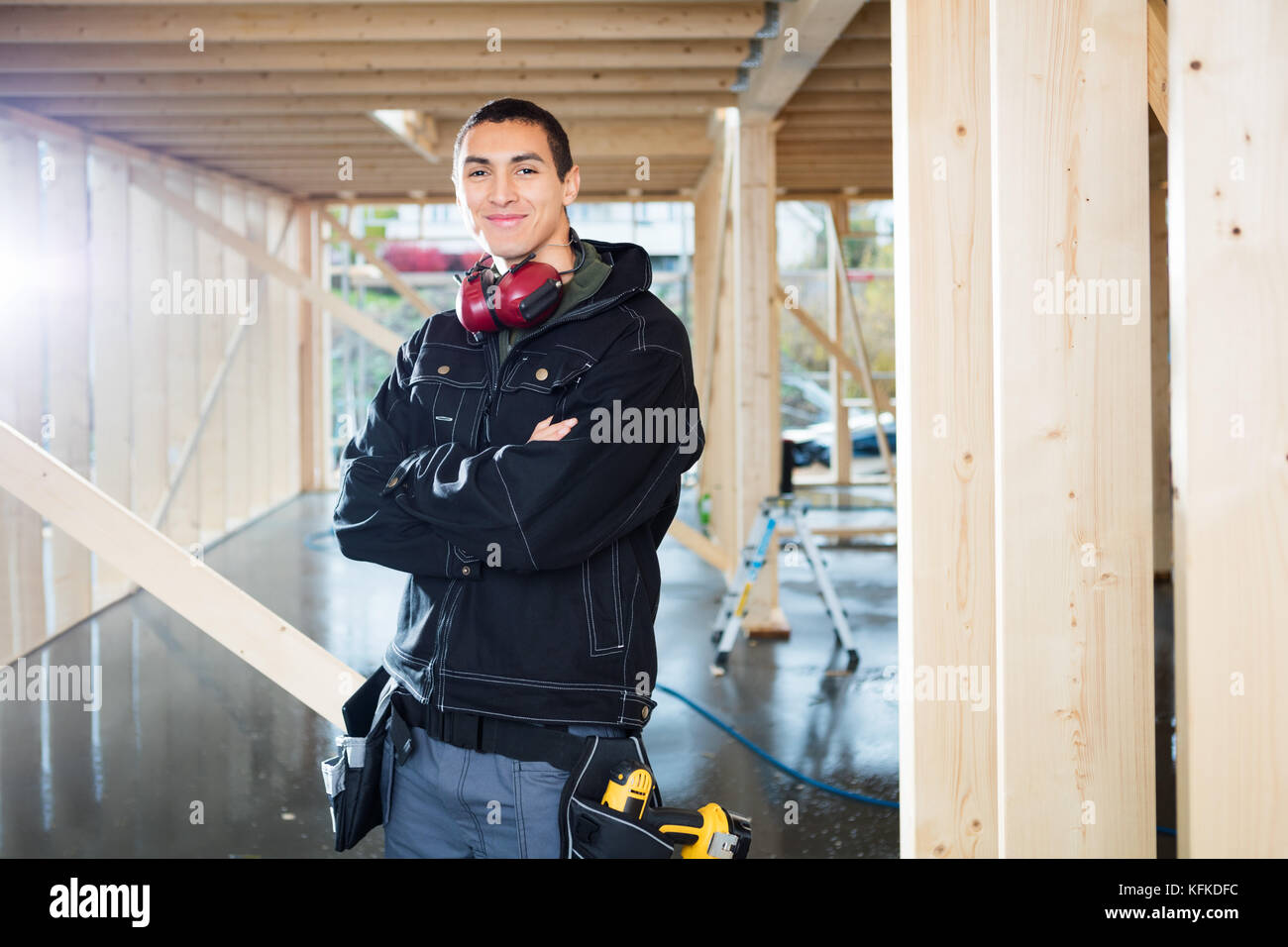 Bello il carpentiere in piedi con le braccia incrociate al sito Foto Stock