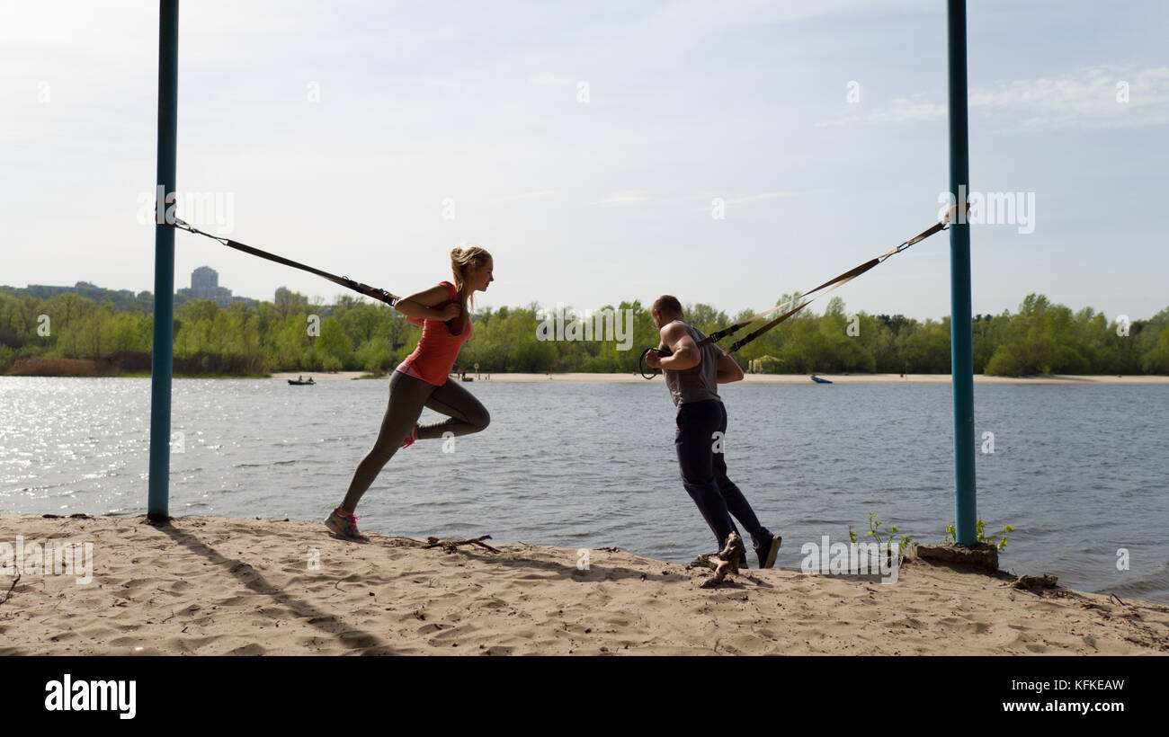 Uomo e donna affondo facendo esercizi con trx ingranaggio. Foto Stock