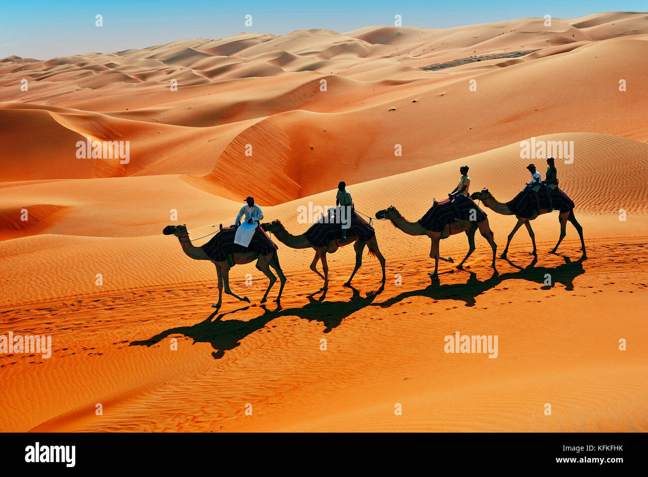 I turisti in cammello di fronte alle alte dune di sabbia, al deserto sabbioso, Rub al Khali, all'Emirato di Abu Dhabi, negli Emirati Arabi Uniti Foto Stock