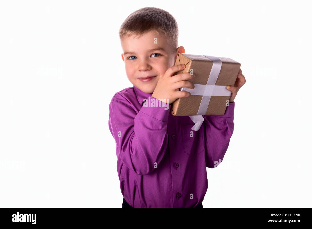 Sorridente divertente bambino tiene un dono nelle sue mani Foto Stock