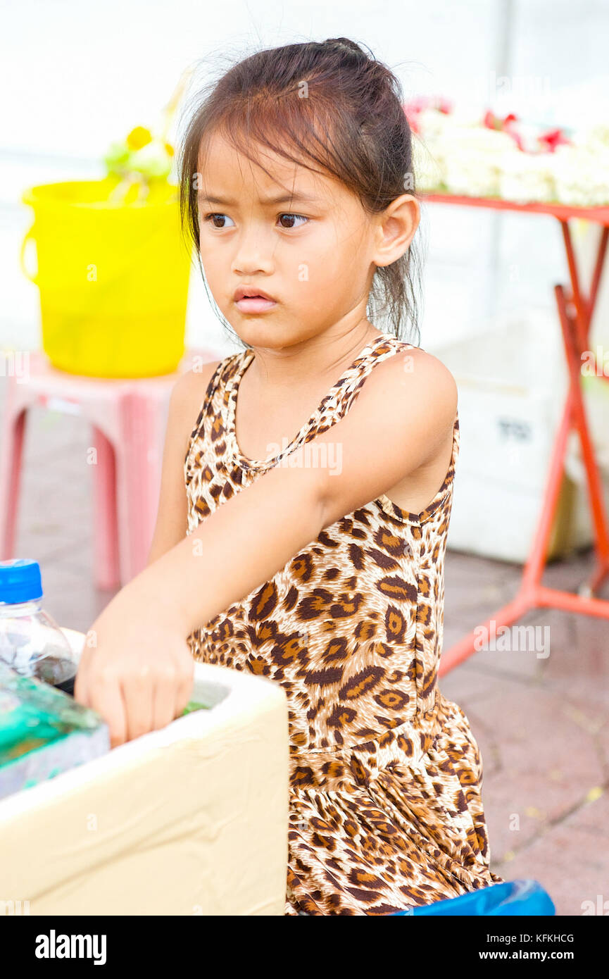 Una piccola ragazza thai aiuta i suoi genitori vendere acqua e rinfreschi in un tempio a Bangkok, in Thailandia. Foto Stock