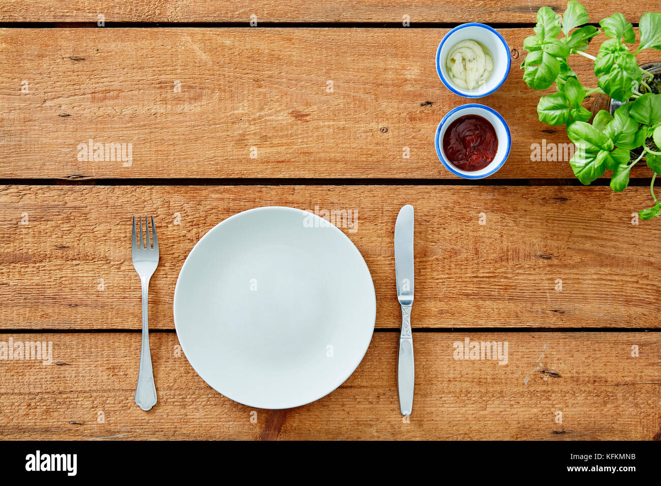 Piastra vuota con coltello e forchetta su materie tavolo in legno Foto Stock