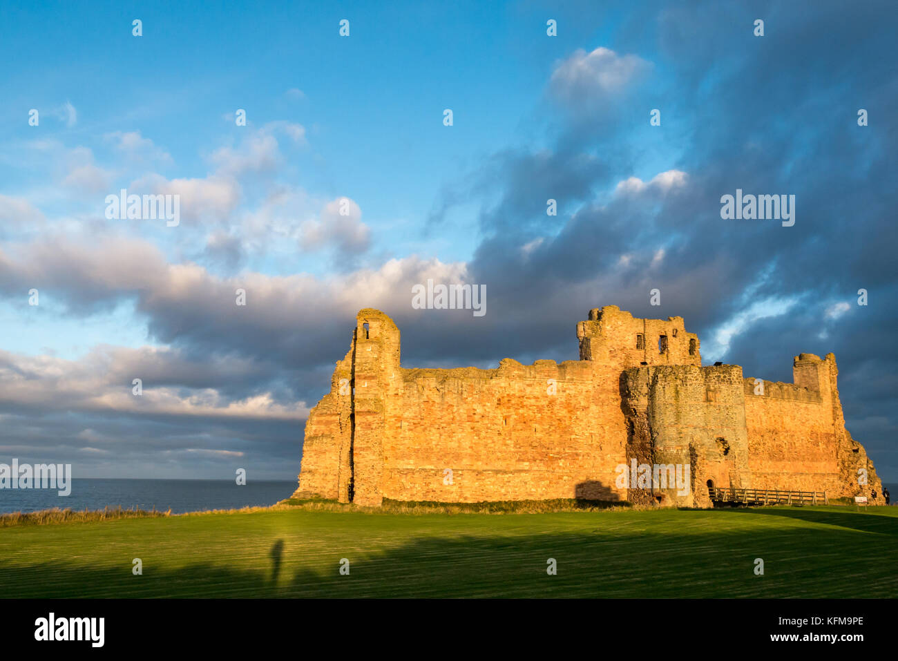 Il crepuscolo della luce del sole sulla parete del XIV secolo rovinato Tantallon Castle, North Berwick, East Lothian costa, Scozia, con lunga ombra del fotografo Foto Stock