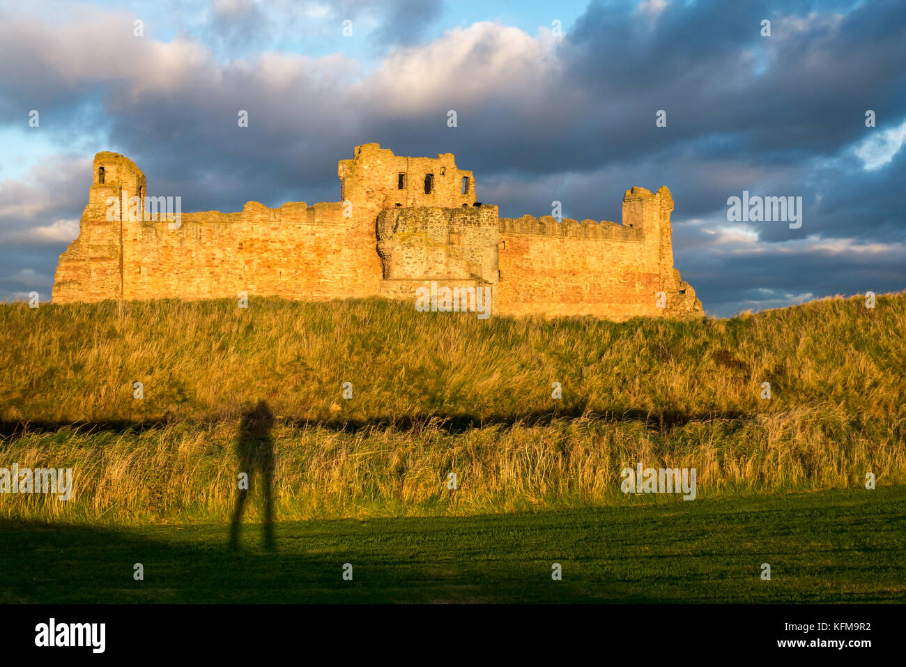 Il crepuscolo della luce del sole sulla parete del XIV secolo rovinato Tantallon Castle, North Berwick, East Lothian costa, Scozia, con lunga ombra del fotografo Foto Stock