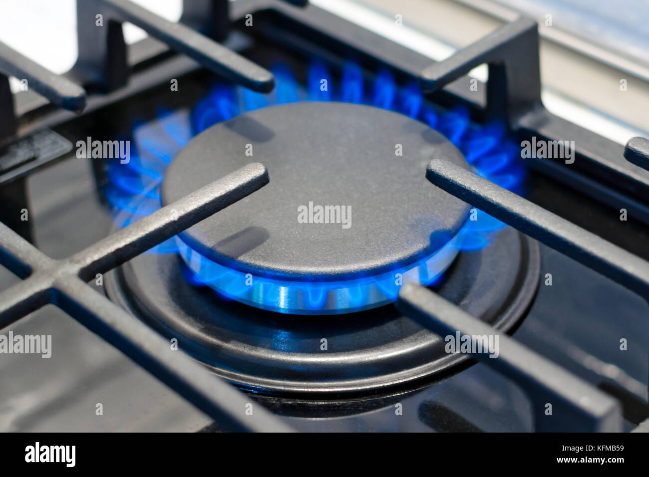 Bruciatore di gas brucia con una fiamma blu sulla stufa sotto la griglia di protezione. foto con profondità di messa a fuoco. Foto Stock