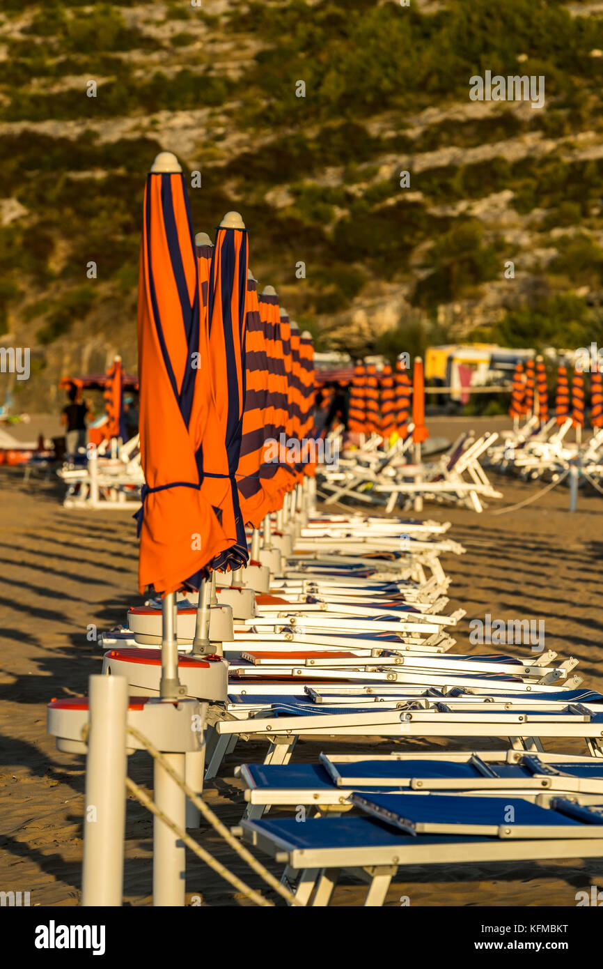 Lettini e ombrelloni sulla spiaggia. Peschici e il Parco Nazionale del Gargano. L'Italia. Foto Stock