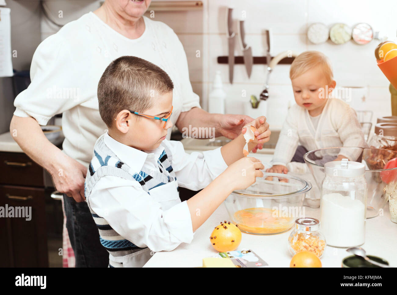 7-anno-vecchio ragazzo aiutare in cucina, rompere le uova in una grande ciotola di vetro. Foto Stock