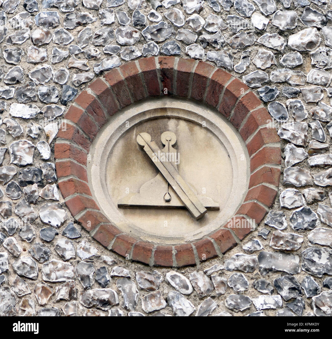 Una regola di piombo e di livello, masonic simboli scolpiti sulla pietra piaghe in una parete di pietra focaia su un vecchio Masonic hall. Winchester, Hampshire, Regno Unito Foto Stock