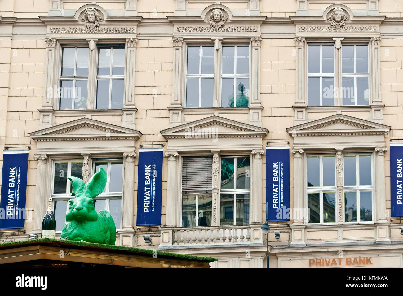 Privat bank a Operngasse. Sul tetto: grandi di plastica verde scultura di coniglio, Cracking Art progetto di installazione. Grande bottiglia di champagne. Vienna, Austria Foto Stock