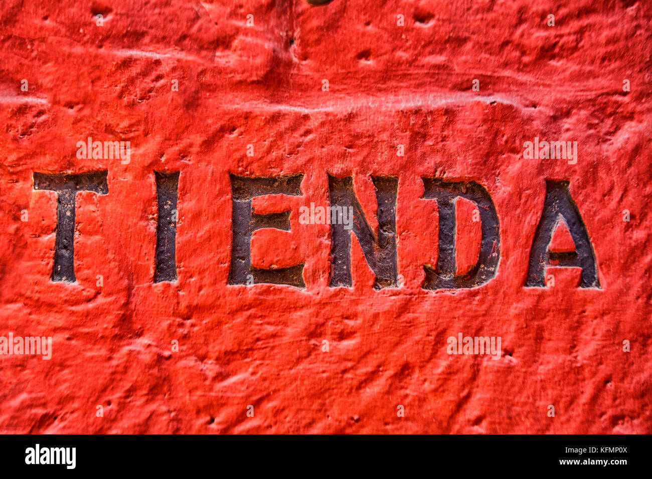 Tienda testo scolpito nel vecchio muro rosso in Perù. tienda è lo spagnolo per il negozio Foto Stock