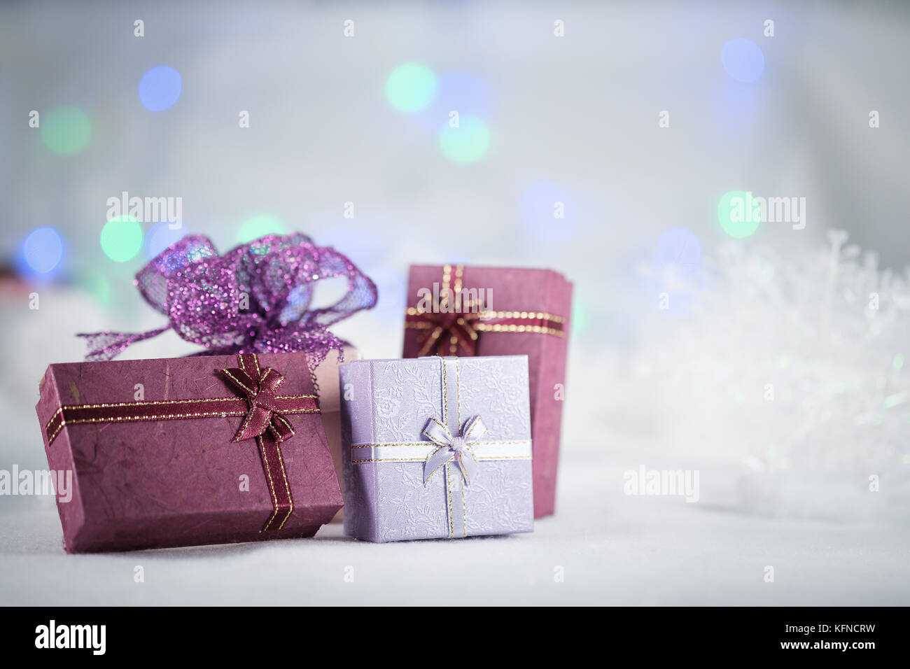 Purole confezioni regalo su la pelliccia bianca su sfondo bokeh di fondo, con copia spazio per stagione saluto. Buon Natale o felice anno nuovo.La selezione del punto af,blur Foto Stock