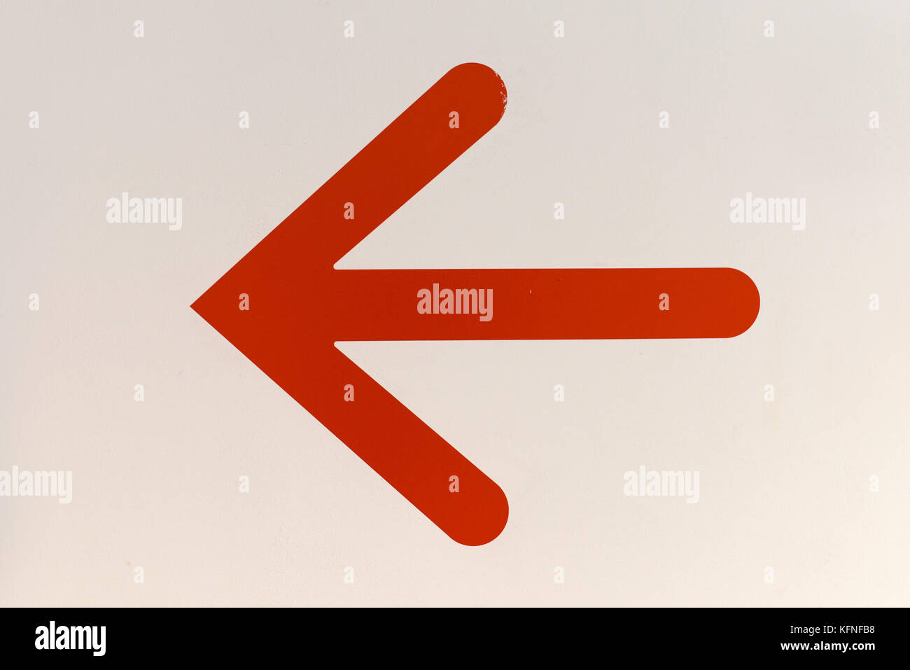 Rosso simbolo di freccia rivolta a sinistra sul muro bianco Foto Stock
