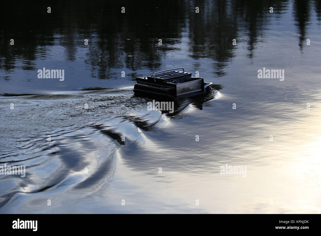 Un telecomando alimentatore controllato in barca in un lago utilizzato nella pesca sportiva. Foto Stock