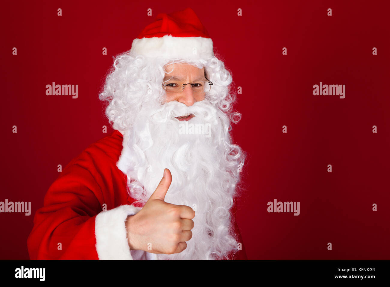 Ritratto di felice santa gesticolando pollice su sfondo rosso Foto Stock