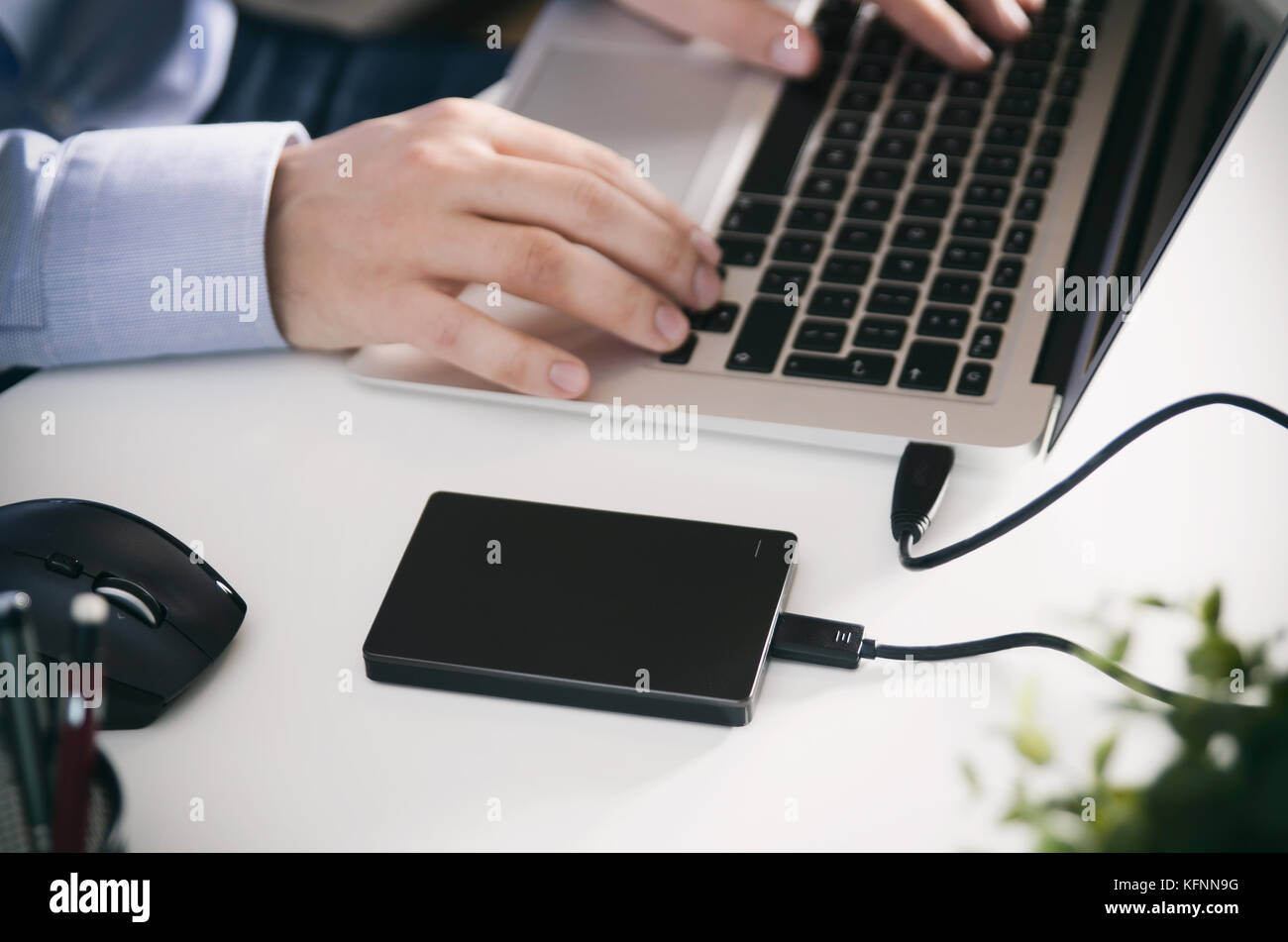 Disco di backup esterno disco rigido collegato al computer portatile. l uomo con i notebook fare della sicurezza dei dati personali copia. Foto Stock