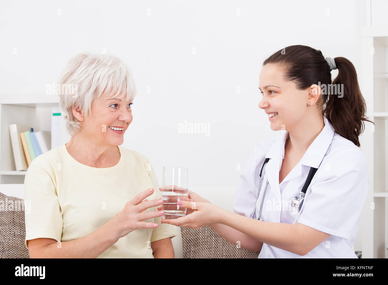 Felice medico che offre un bicchiere di acqua al paziente maturo Foto Stock