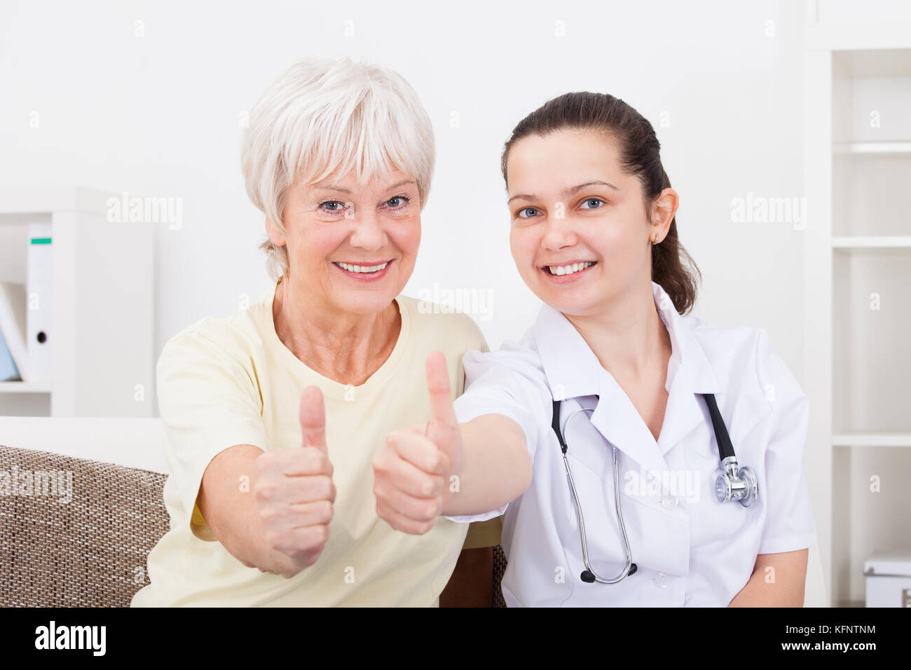 Felice giovane medico e paziente senior che mostra il pollice in alto segno Foto Stock