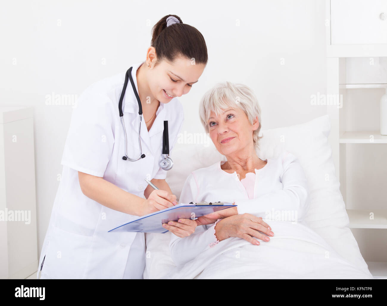 Senior paziente femmina guardando medico iscritto negli appunti Foto Stock