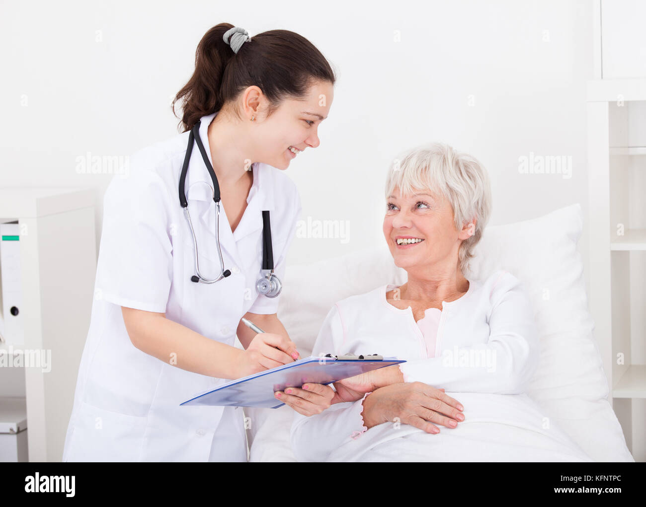 Senior paziente femmina guardando medico iscritto negli appunti Foto Stock