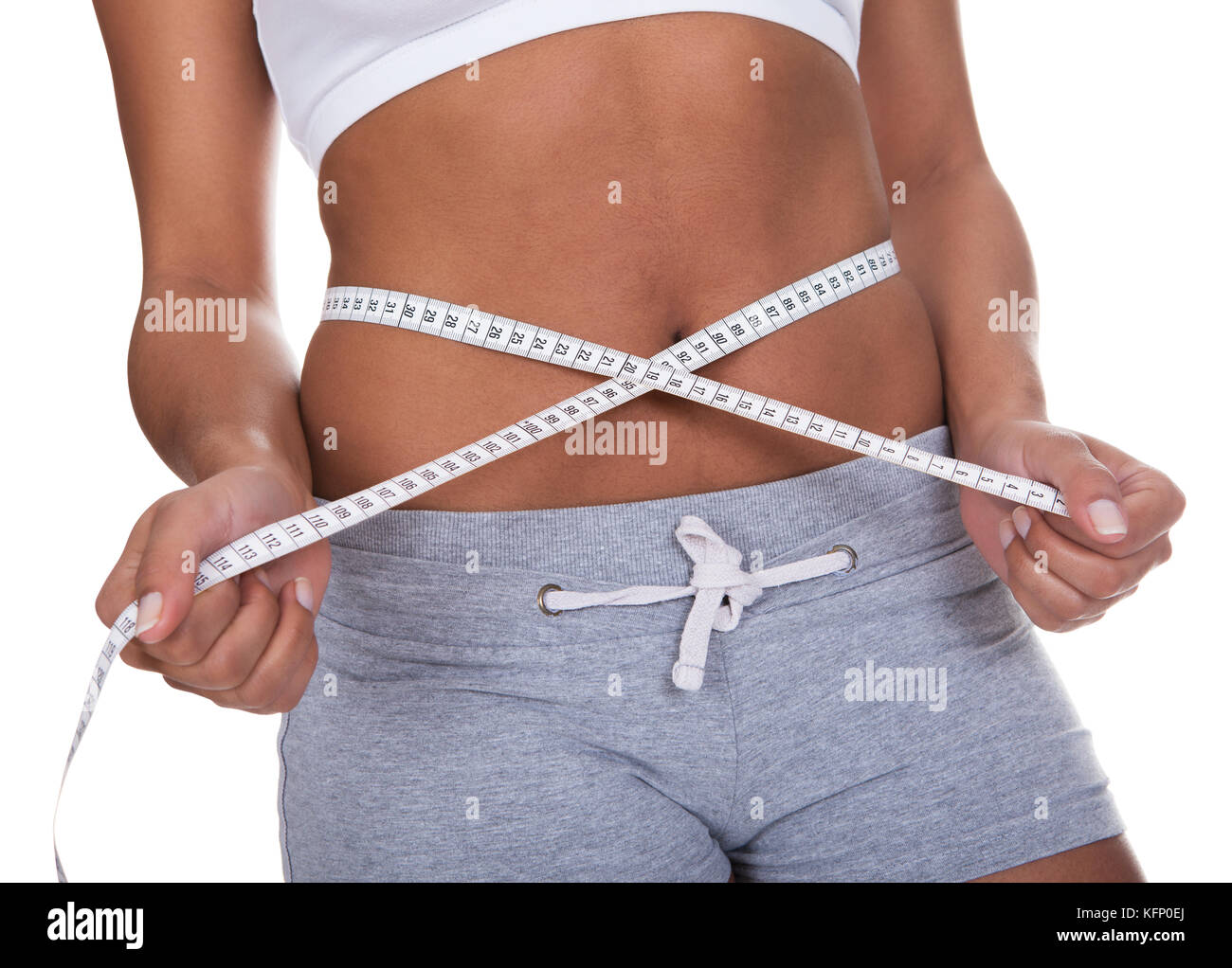 Ritratto di giovane donna misurando il suo girovita su sfondo bianco Foto Stock