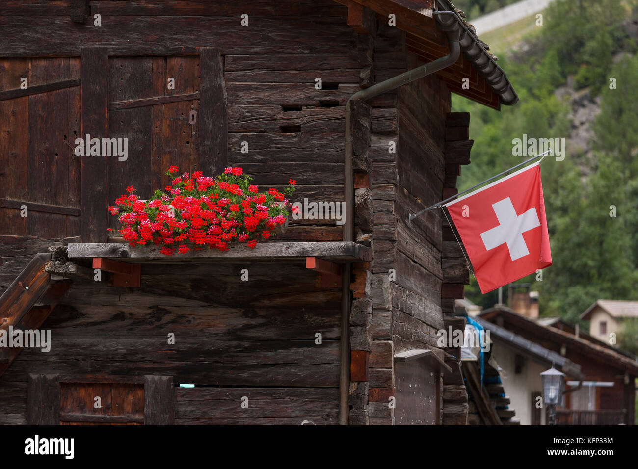 Herbriggen, Svizzera - tradizionale edificio in legno con fiori e bandiera svizzera. Foto Stock
