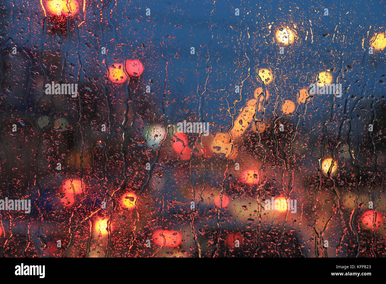 Le gocce di pioggia sul parabrezza. il traffico della strada luce astratta bokeh luce sfocati. Sfondo. Foto Stock