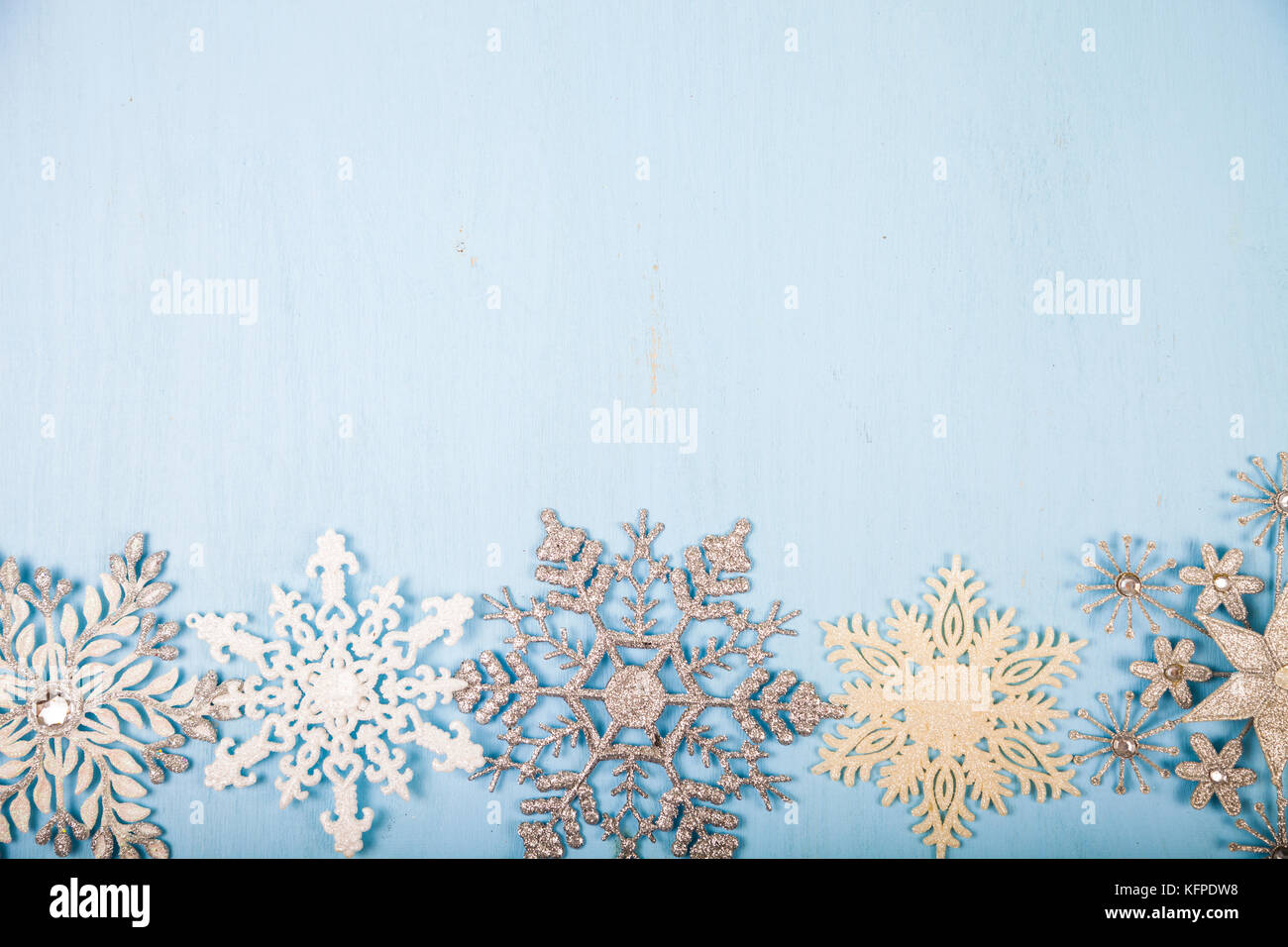 Fiocchi di neve argenteo su un blu sullo sfondo di legno. decorazioni di Natale. Foto Stock
