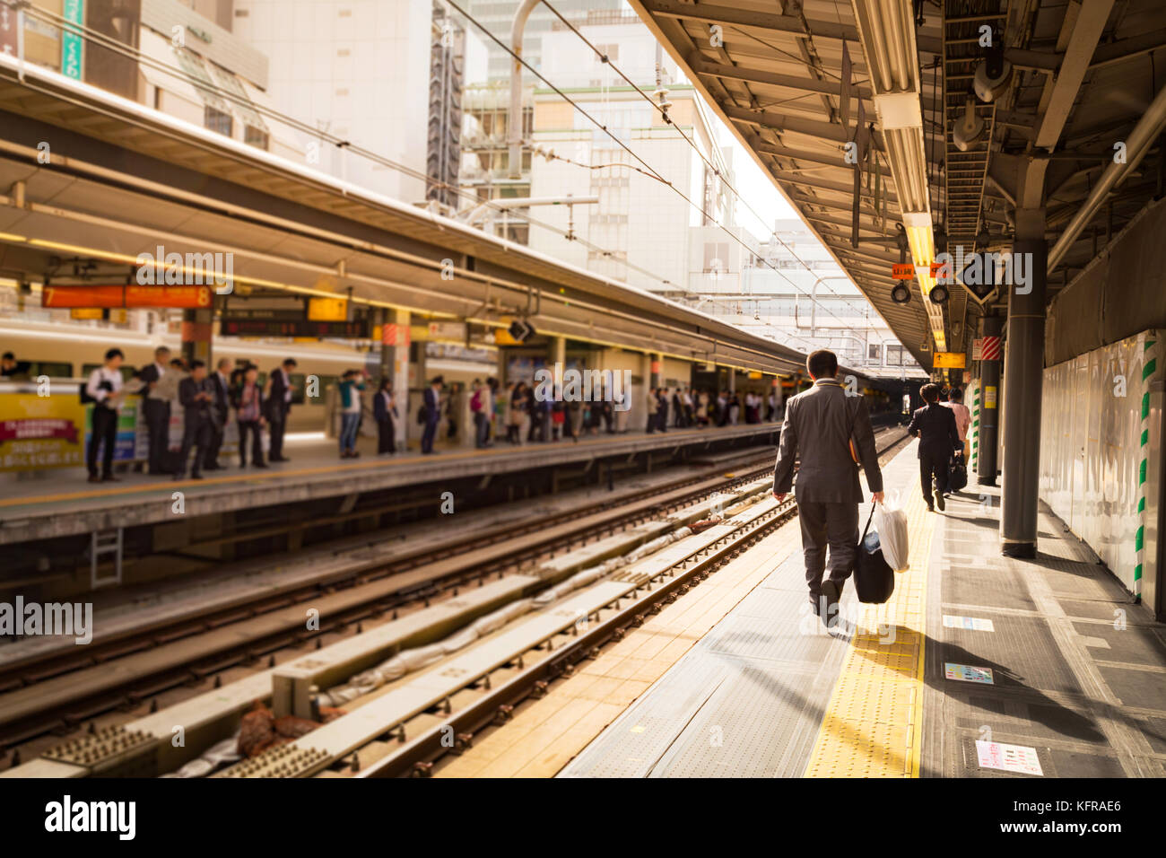 Imprenditore che arrivano alla stazione ferroviaria nella luce del sole di mattina e di andare a lavorare in città. Il fuoco selettivo. Foto Stock