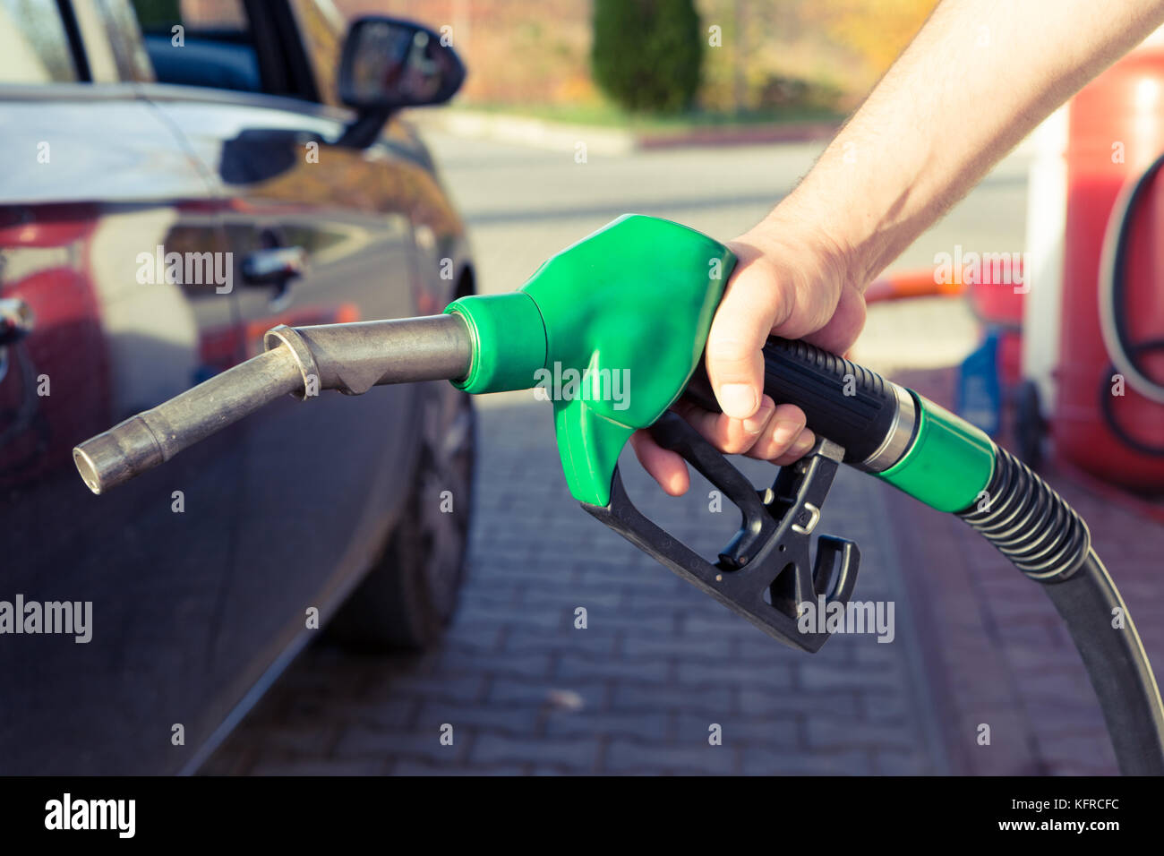 Man mano che tiene la pompa di benzina in una stazione di benzina per riempire il serbatoio o per fare rifornimento di combustibile costoso concetto con aumento di prezzo Foto Stock