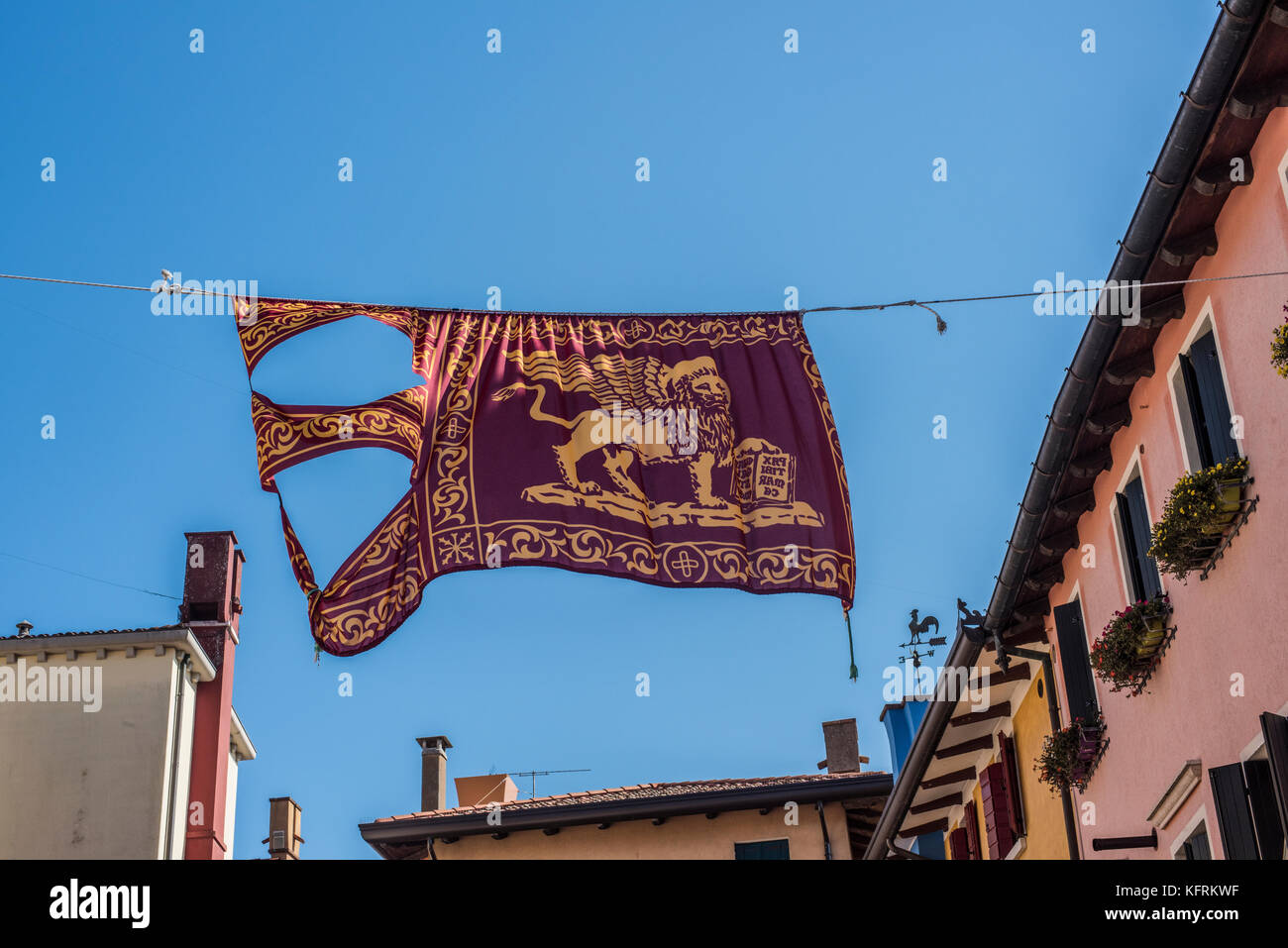 La bandiera veneziana sospeso sopra il rio terra, Caorle, Veneto Foto Stock
