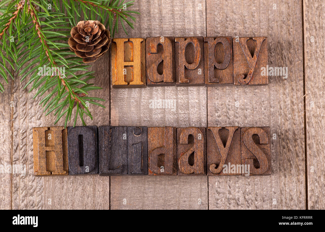 Vacanze felici del testo su una superficie in legno con albero sempreverde di diramazione e di pigna Foto Stock