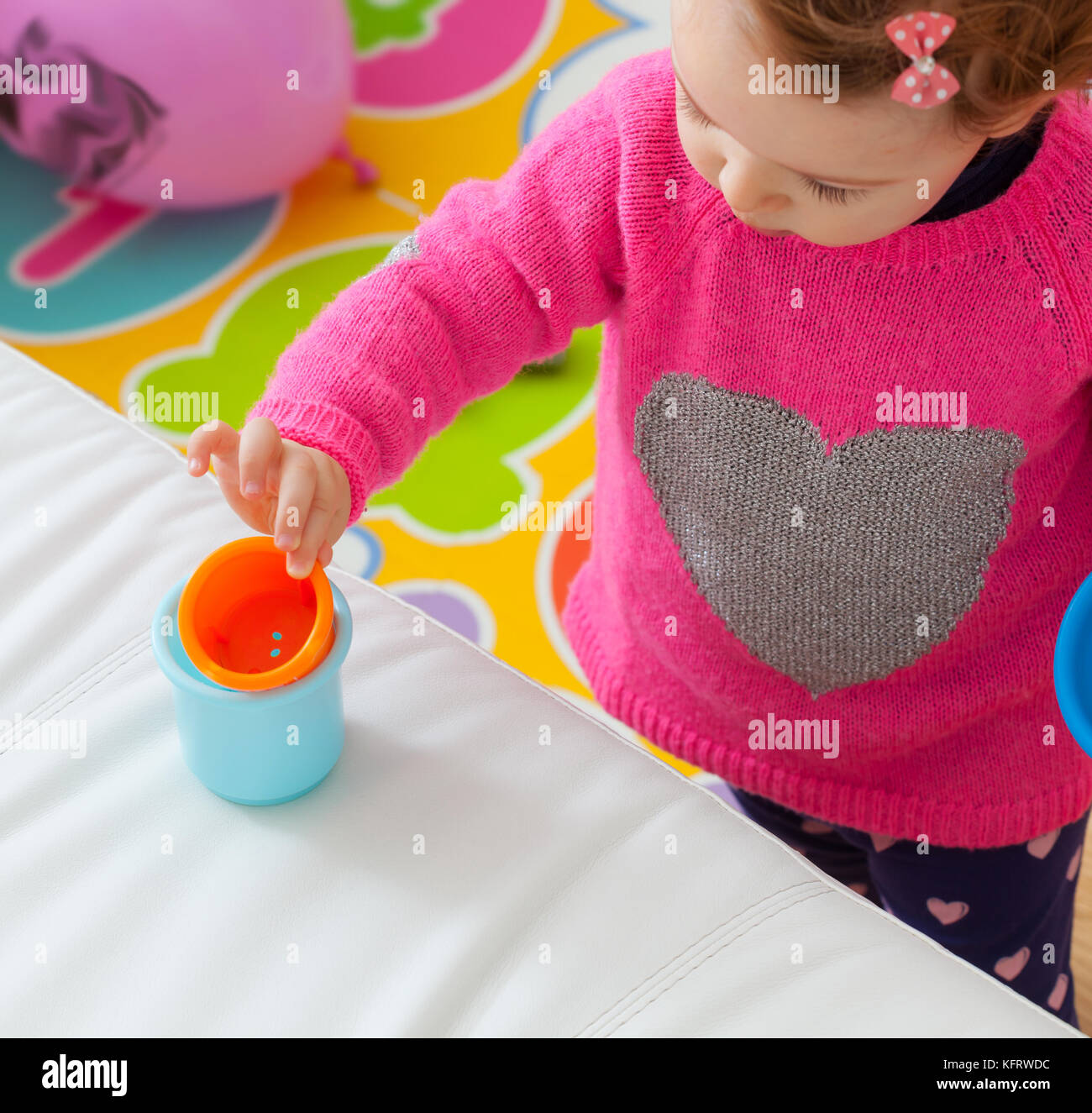 Bimbo bimba gioca con tazze colorate, giocattoli per lo sviluppo cognitivo. Foto Stock