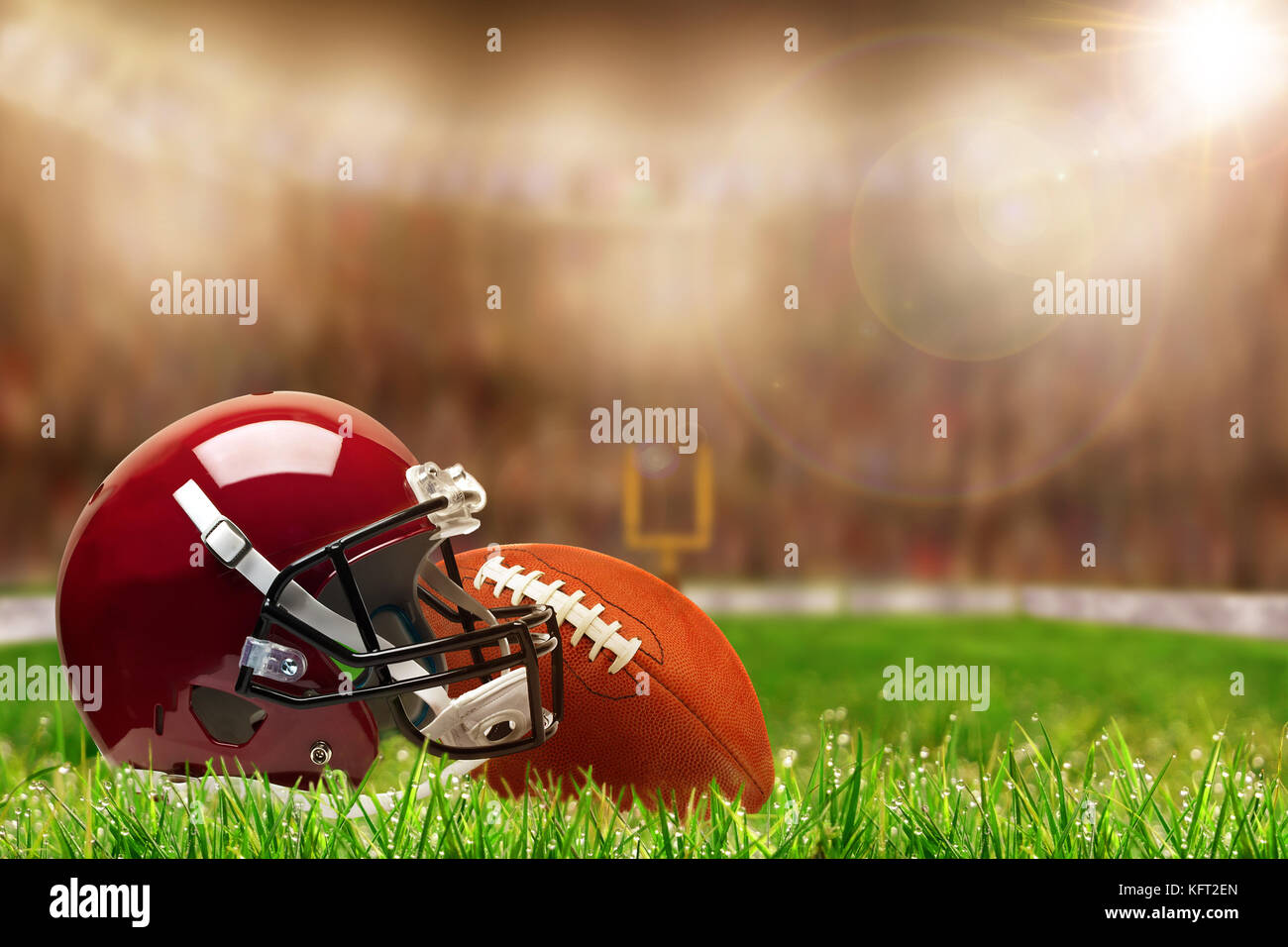 Basso angolo vista di casco da football americano e la palla sul campo in erba deliberata e profondità di campo sulla luminosa sullo sfondo dello stadio con copia spazio. Foto Stock