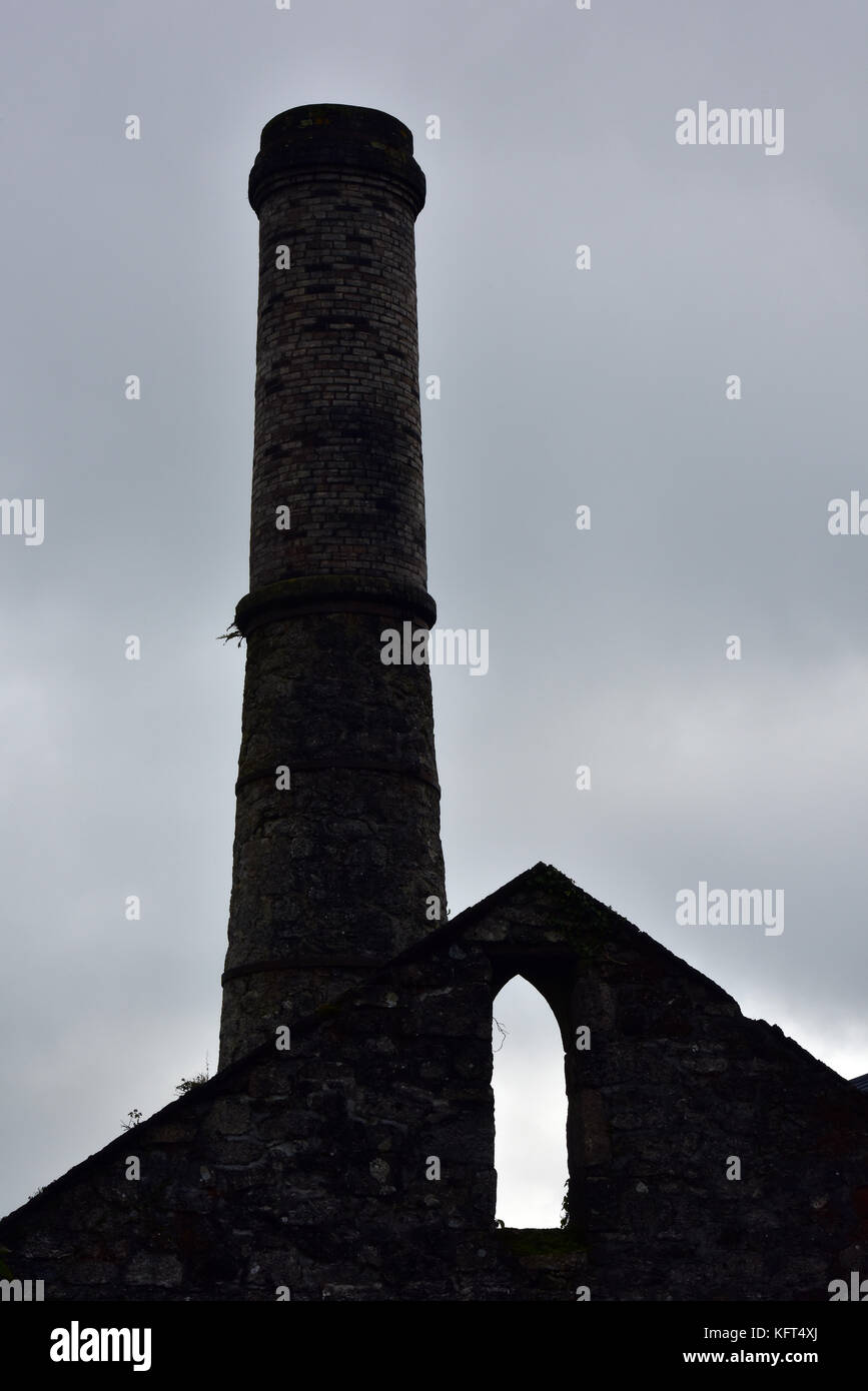 Le rovine di un cornish china clay o stagno motore di data mining casa con il camino in aumento nell'aria stagliano grigio e imponente sky. Cornwall. Foto Stock