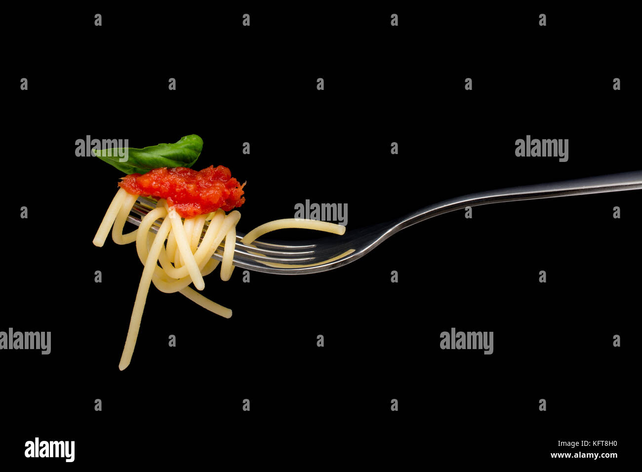 La pasta in sfondo nero. spaghetti, pomodoro e basilico sulla forcella. cucina italiana concept Foto Stock